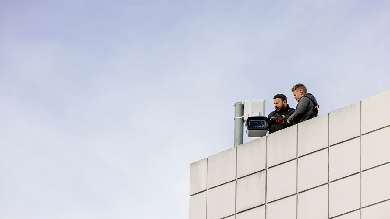 Two men installing the Panomera surveillance camera on a rooftop